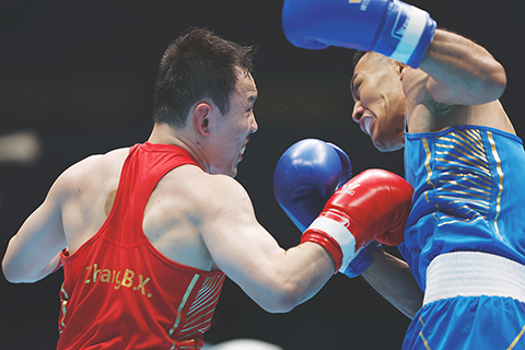 ◎ 十一月十一日,在深圳市寶安體育中心體育館舉行第十五屆全國運動會拳擊項目男子七十一公斤級半決賽中,北京隊烏勒怕爾·哈爾恒(藍衣)戰勝中國公安體育協會隊張博雄(紅衣)順利晉級。(中新社記者 韓海丹 攝)