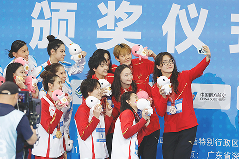 ◎ 十一月十日,在深圳大運中心游泳館舉行第十五屆全國運動會游泳項目女子四乘一百米自由泳接力的決賽中,由葛楚彤、王一淳、張昕煜、楊浚瑄組成的山東隊奪得金牌。圖為獲獎選手在領獎台上自拍留影。(中新社記者 韓海丹 攝)