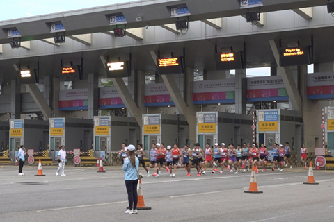 ◎ 十一月十五日,第十五屆全國運動會馬拉松比賽早上舉行,賽事以深圳灣公路大橋為紐帶,跨越深港兩地,是全運會歷史上首個跨境馬拉松賽事。男子組賽事於上午七時出發,而女子組賽事則於上午七時三十分出發,選手跑約兩公里經深圳灣口岸進入香港,口岸旁邊有啦啦隊打氣。(香港中通社朱樂怡 攝)