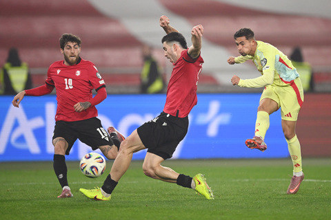 ◎ 十一月十五日,在格魯吉亞第比利斯舉行的二0二六年世界盃E組預選賽格魯吉亞和西班牙之間的足球比賽中,西班牙選手葉里米.皮諾(右) 球直闖禁區,格魯吉亞選手盧卡.洛霍什維利(中)忙阻攔他。(美聯社/TamunaKulumbegashvili)