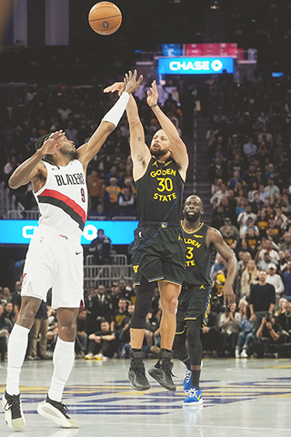 ◎ 金州勇士後衛史蒂芬·居里(30)在十一月二十一日於三藩市舉行的NBA常規賽下半場投進三分球,波特蘭拓荒者前鋒傑拉米.格蘭特(9)封阻不果。(美聯社/Godofredo A. Vasquez)