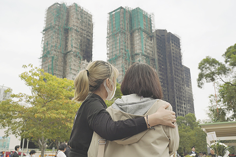 ◎ 香港大埔宏福苑日前發生五級大火,造成嚴重傷亡。警方十二月三日下午舉行記者會交代最新情況時表示,截至當天十四時,最新遇難者人數升至一百五十九人,其中一百四十具遺體已初步確認身份。圖為民眾遙望滿目瘡痍的大埔火災現場。(香港中通社陳奕啟 攝)