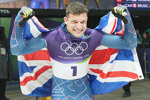 ◎ 2月13日晚,冬奧會男子鋼架雪車比賽在科爾蒂納滑行中心繼續進行。英國選手馬特.韋斯頓延續統治,在該項目四輪滑行中四次刷新賽道紀錄,最終以總成績3分43秒33奪冠。圖為馬特.韋斯頓在賽後身披國旗慶祝。(中新社記者崔楠 攝)