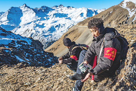 ◎ 在西藏山南市隆子縣玉麥鄉境內,護邊員拉巴次仁(右)在清理灌進鞋裡的沙石和積雪(二月六日攝)。