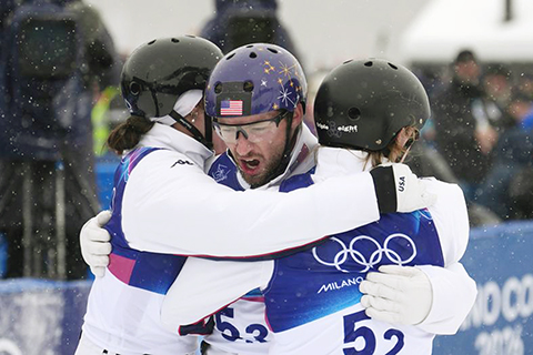 ◎ 2月21日,美國隊選手利利斯(中)在第二輪比賽後擁抱隊友。最終,美國隊獲得金牌。冬奧會自由式滑雪空中技巧混合團體決賽在意大利利維尼奧舉行。(新華社記者 胡超 攝)