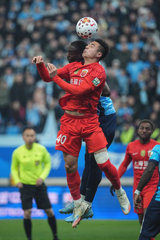 ◎ 三月二十日,上海海港隊球員吾米提江.玉蘇普(前)爭頂頭球。中國足球協會超級聯賽第三輪比賽中,大連英博隊主場一比零戰勝上海海港隊。(新華社記者 潘昱龍 攝)
