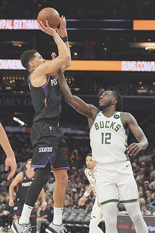 ◎ 三月二十一日在鳳凰城斯舉行的NBA常規賽下半場,鳳凰城斯太陽隊後衛德文·布克(1)超過密爾沃基雄鹿隊前鋒托里恩·普林斯(12)投籃。是役,太陽以一百零五比一百零八不敵公鹿。(美聯社/里克·斯庫特里)