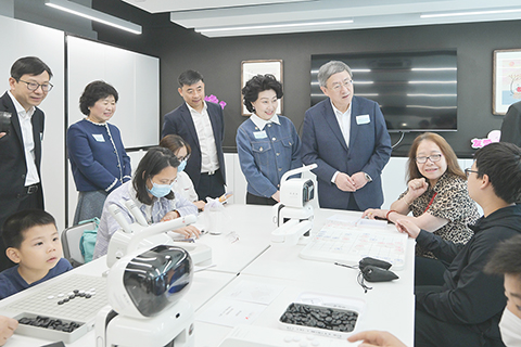 ◎ 三月三十日,位於香港旺角的第十一間社區客廳舉行開幕儀式,為區內基層家庭提供額外生活空間與多元支援;並首次融合科技與人文,是首家引入AI及穆斯林專用設施的項目。旺角社區客廳實用面積約五千三百平方呎,預計每年可服務五百個家庭,全年服務八萬人次。圖為嘉賓與正在體驗AI智能下棋活動的受惠家庭交流。(香港中通社)