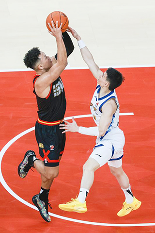 ◎ 四月二日,深圳馬可波羅隊球員賀希寧(左)投籃。CBA常規賽第三十三輪比賽中,深圳馬可波羅隊主場一百零九比九十四戰勝浙江浙商證券隊。(新華社發 彭志剛 攝)