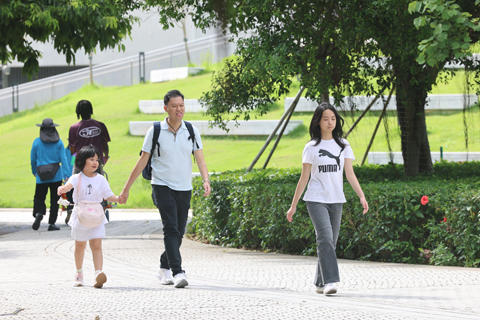 ◎ 六月廿一日,端午小長假尾日,亦是父親節。香港西九文化區海濱公園旁,不少家庭趁假期最後一天陪同子女外出享受陽光。現場氣氛溫馨融洽,眾多父親與子女在草坪上嬉戲玩耍,亦有家庭沿着海濱長廊騎行單車,享受假日時光。圖為市民攜小朋友在西九文化區出行。(香港中通社記者 鄧梓傑 攝)